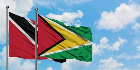 147564660-trinidad-and-tobago-and-guyana-flag-waving-in-the-wind-against-white-cloudy-blue-sky-together